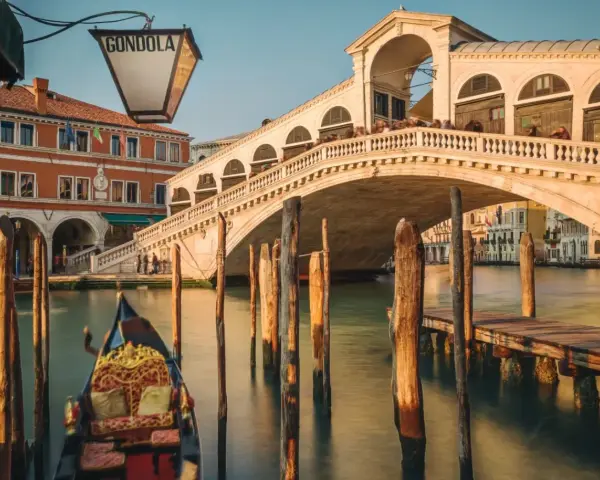 Gondola ferma in un canale di Venezia inverno, con il Ponte di Rialto sullo sfondo.