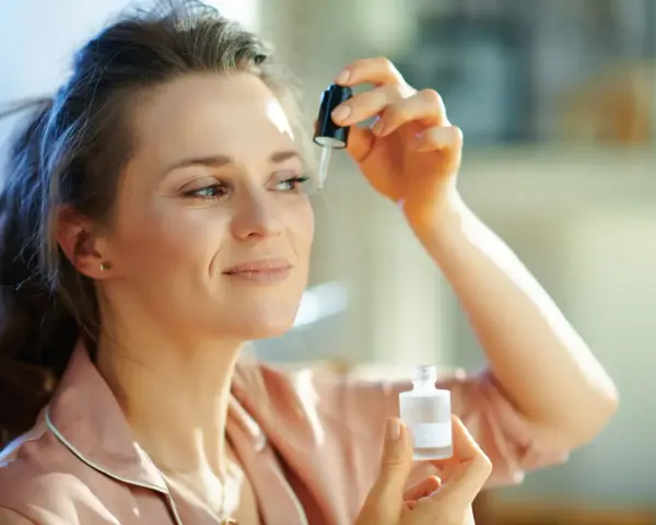 Kobieta aplikuje serum z **retinalem** na skórę pod okiem, dbając o młody wygląd.