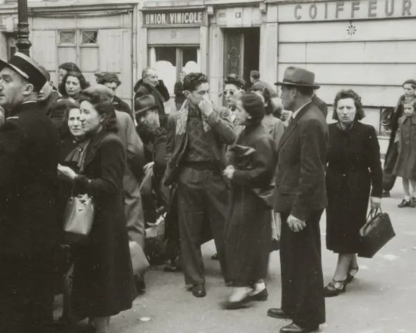 Une foule se presse devant "Union Vinicole" et "Coiffeur". L'atmosphère est tendue, évoquant la rafle du billet vert.