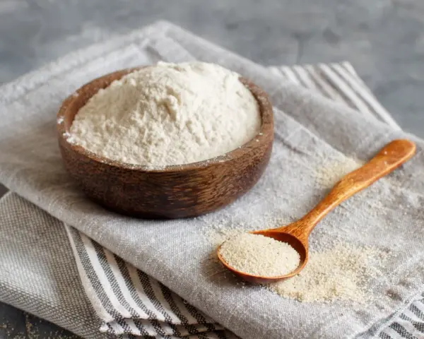 Mąka gryczana w drewnianej misce i na łyżce. Czy mąka gryczana ma gluten? Nie, jest bezglutenowa.