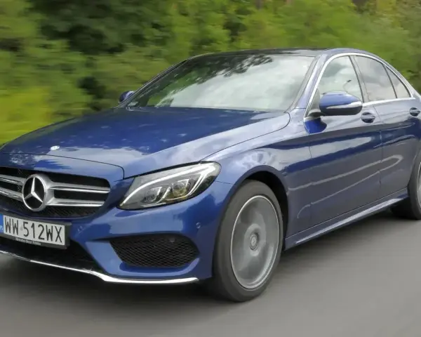 Błękitny Mercedes E220d w ruchu, z rozmytym tłem zieleni i drogi. Elegancki sedan na polskich tablicach rejestracyjnych.