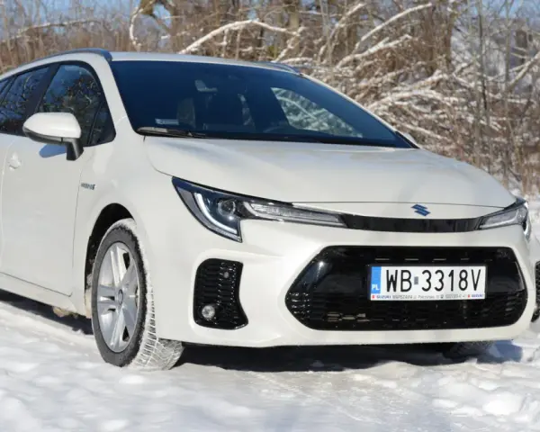 Biały Suzuki Swace Hybrid na śniegu, gotowy na zimowe wyzwania.