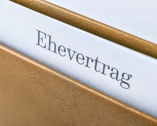 Ein Ehevertrag in einem braunen Ordner. Die Frage, ob man einen Ehevertrag aufheben ohne Notar kann, beschäftigt viele.