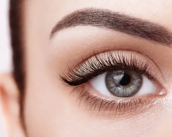 Ojo de mujer con pestañas largas y cejas definidas. Descubre cómo hacer crecer las pestañas para una mirada impactante.