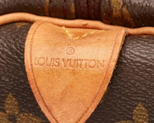 Etichetta in pelle con logo Louis Vuitton, un dettaglio iconico che evoca la maestria della fabbrica Louis Vuitton.