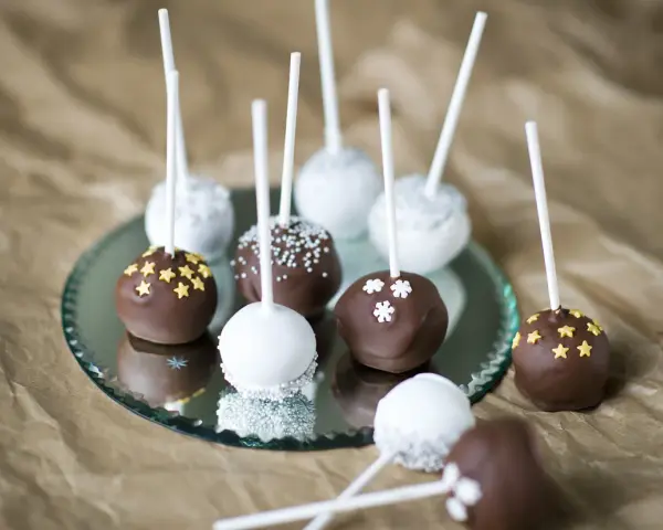 Läckra cakepops med choklad och vit glasyr, dekorerade med stjärnor och snöflingor. Ett enkelt cakepops recept att prova!