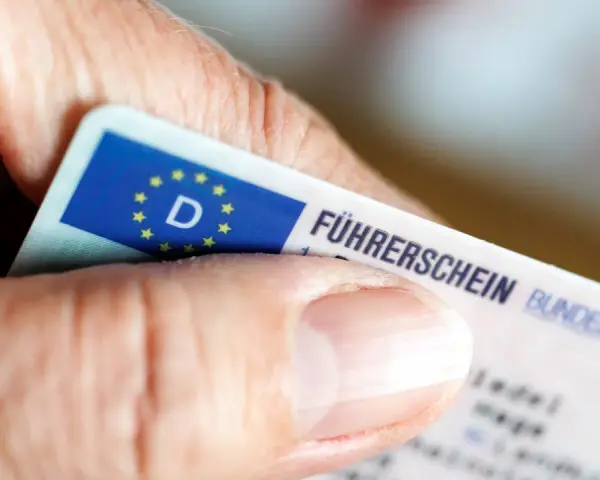 Nahaufnahme eines Führerscheins, der von einer Hand gehalten wird. Die Person könnte versucht sein, trotz Fahrverbot zu fahren.