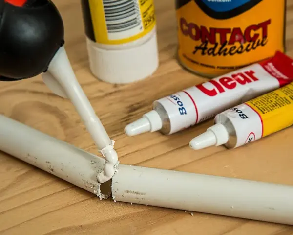 Klej w tubce i pistolet do klejenia na drewnianym blacie. Zastanawiasz się, czym usunąć klej super glue z mebli?