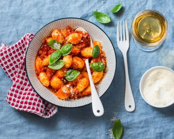 Pyszne gnocchi w sosie pomidorowym, posypane parmezanem. Idealne z kieliszkiem białego wina.