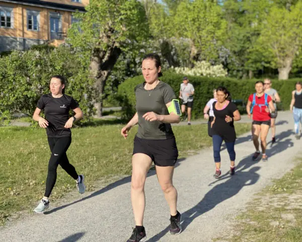 En grupp löpare på en grusväg, en del med fokus på att få upp konditionen snabbt. Solen skiner och träden är gröna.