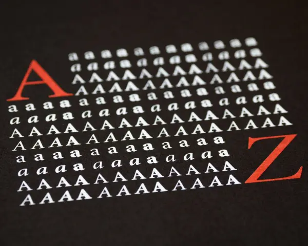 Duża czerwona litera "A" i rzędy białych liter "a" i "A" na czarnym tle, ilustrujące **kerning**. Obok czerwona litera "Z".