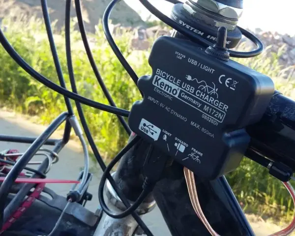 Ładowarka rowerowa Kemo zasilana przez **dynamo**, podłączona do kierownicy, z kablem USB.