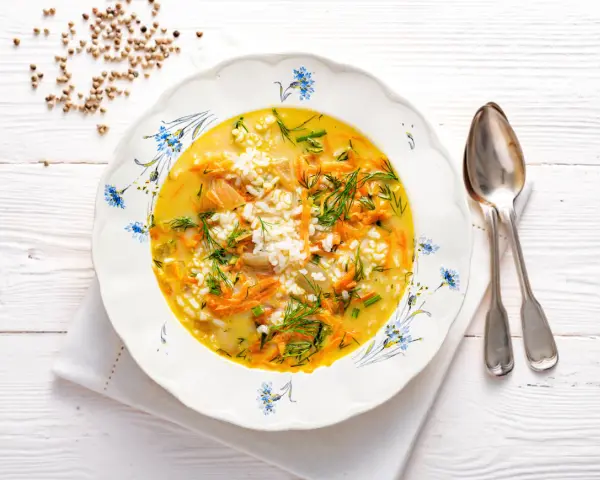 Aromaticzna zupa koperkowa z ryżem, marchewką i kawałkami kurczaka, udekorowana świeżym koperkiem.