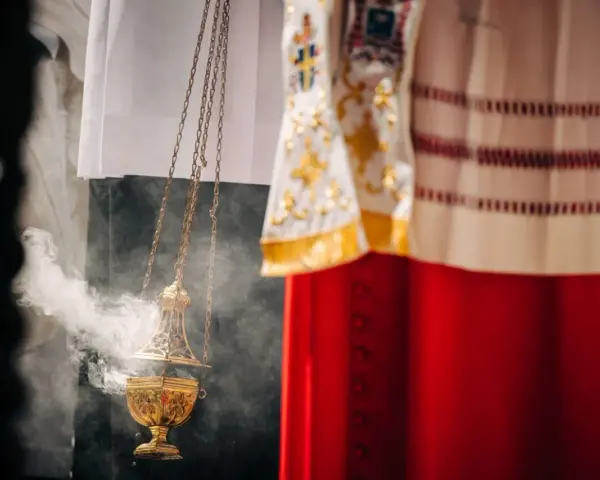 Złota kadzielnica unosi dym podczas uroczystości. W tle widać szaty liturgiczne, przypominające o święta nakazane.