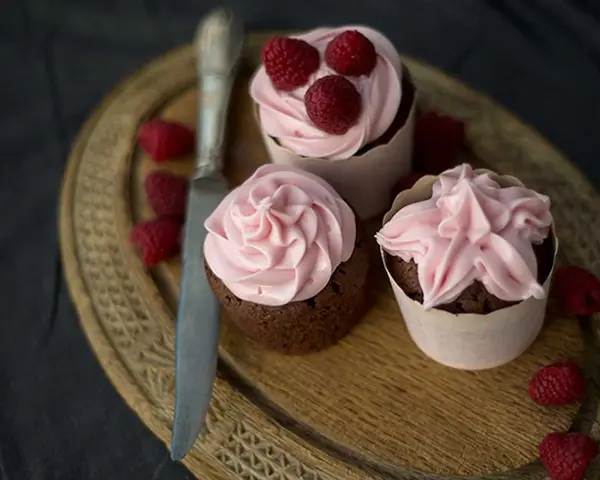 Tre chokladcupcakes med rosa frosting och hallon, redo att avnjutas. Ett perfekt cupcakes recept för alla tillfällen.