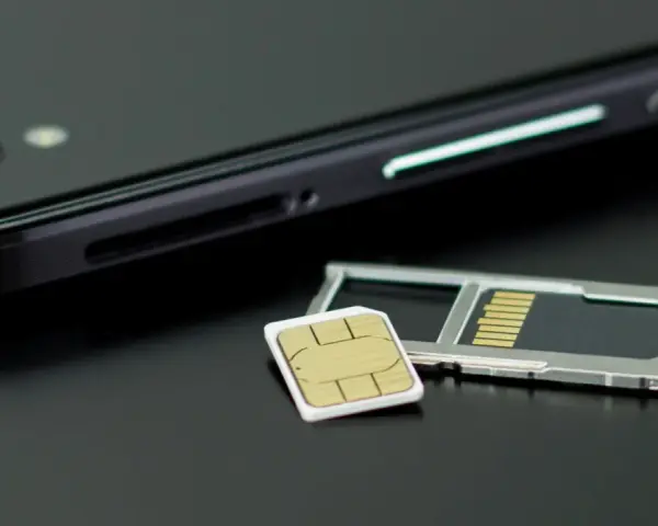 En mobiltelefon och ett SIM-kort bredvid SIM-kortshållaren. Kanske dags att byta SIM-kort för att kunna ringa utan simkort?