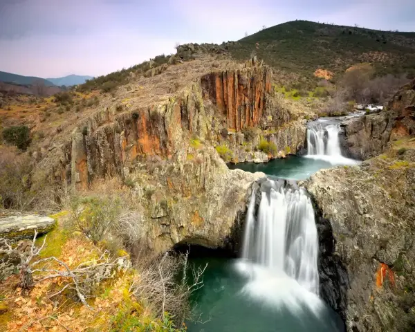Cascadas en el río Guadalajara, rodeadas de rocas rojizas y vegetación otoñal.