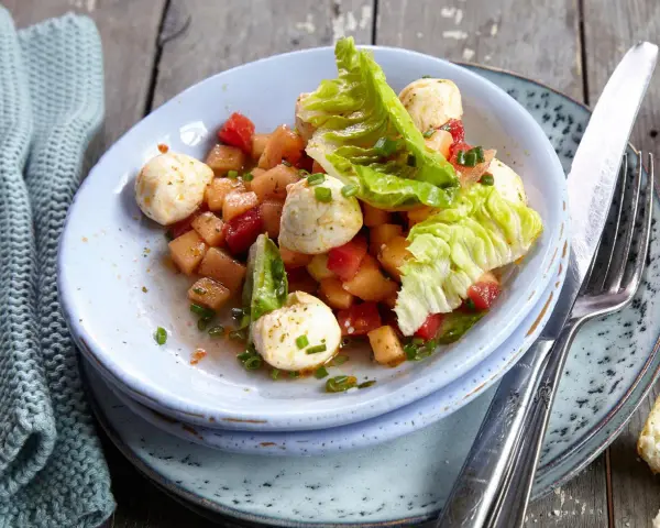 Erfrischender melonensalat mit mozzarella, Tomaten und knackigem Salat. Ein leichter Genuss für warme Tage.