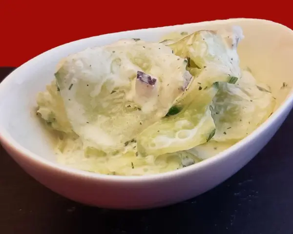 Salade fraîche de concombre à la crème, parsemée d'herbes fines. Un délice léger et savoureux.