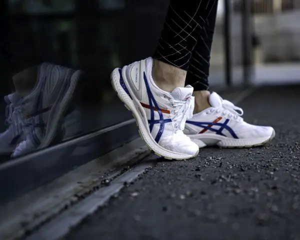 Vita Asics-skor med blå och röda detaljer, perfekt för löpning. Kolla in vår asics storleksguide för rätt passform.