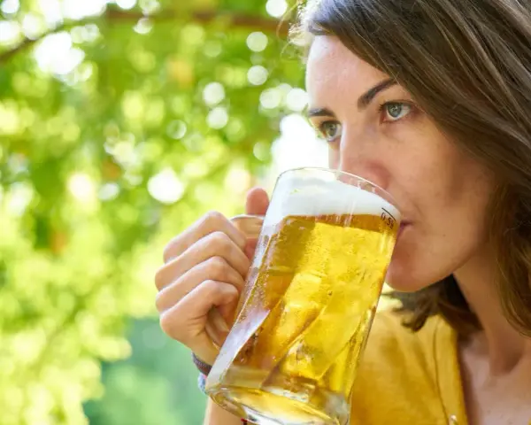 Frau genießt ein kühles Bier im Freien. Vielleicht eine der vielen nordischen Biersorten, die sie entdeckt.