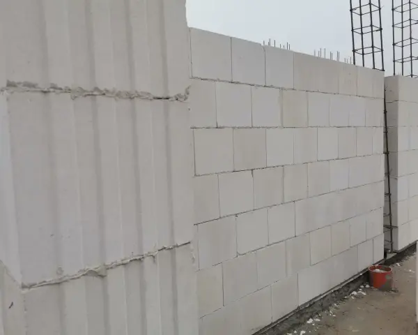 Ściana z bloczków silikatowych wznoszona na budowie. Widać zbrojenie i fragmenty fundamentów.