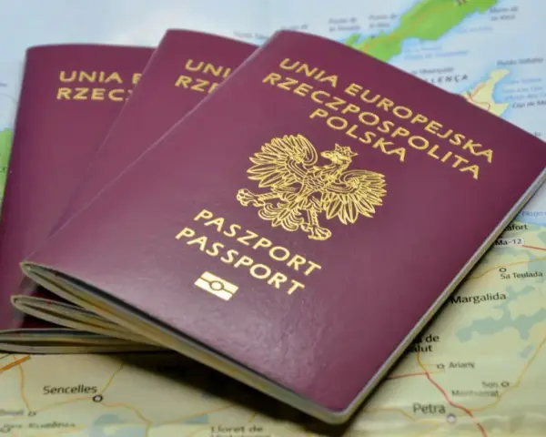 Trzy polskie paszporty leżą na mapie, gotowe do podróży. Opłata za paszport to niewielka cena za wolność odkrywania świata.