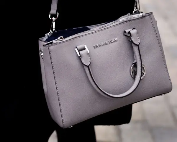 Szara torebka Michael Kors, znanej firmy z luksusowymi akcesoriami, z widocznym logo.