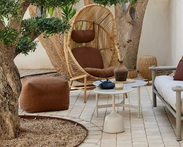 Gemütlich die **terrasse gestalten**: Rattan-Sessel, bequeme Sitzbank, Pouf und kleine Tische laden zum Verweilen ein.