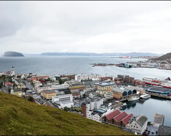 Vy över en stad vid havet med färjor vid kaj. En kyrka med högt torn syns i förgrunden. Detta är Norges nordligaste stad.