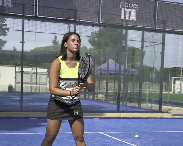 Giocatrice di padel con racchetta, pronta a scendere in campo. Ecco come vestirsi per giocare a padel: top tecnico e gonna sportiva.