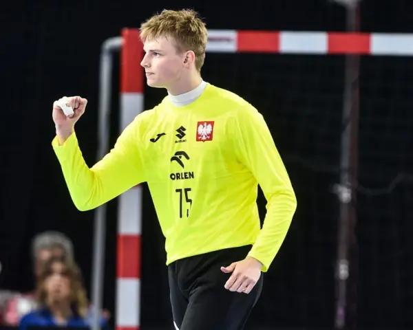 Marcel Jastrzębski, młody bramkarz w żółtej koszulce z orłem, zaciśniętą pięścią świętuje udaną interwencję.