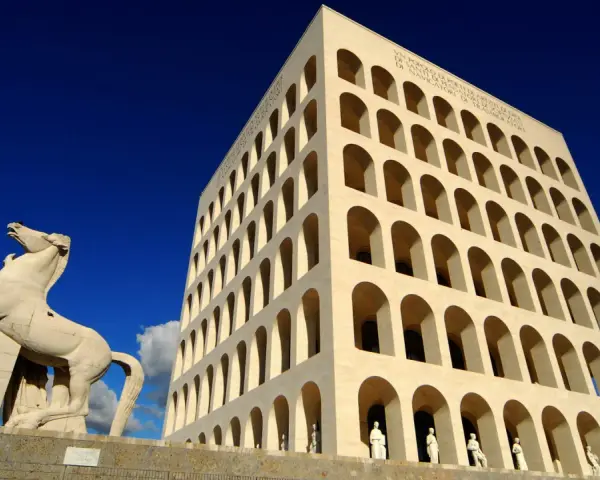 Le palais de la civilisation italienne, monument emblématique, se dresse fièrement sous un ciel bleu éclatant, avec une statue de cheval en avant-plan.
