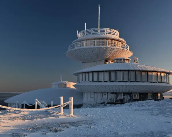 Lodowy pałac na szczycie w Karkonoszach. Budynek obserwatorium pokryty szronem, otoczony zimowym krajobrazem.