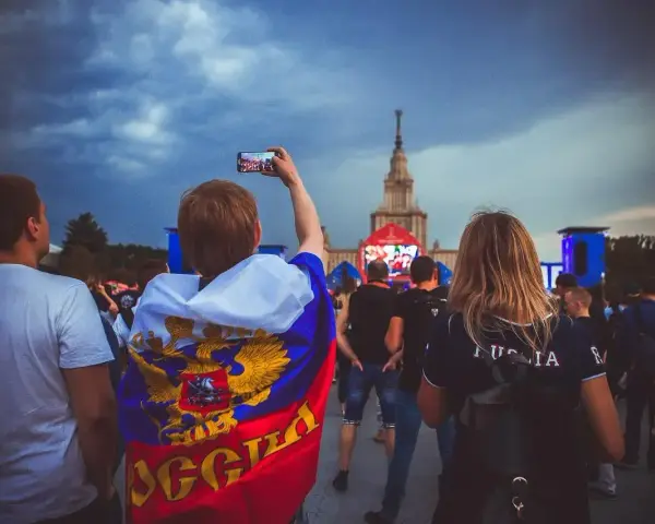 Fani w moskiewskim klubie piłkarskim, jeden z nich z flagą Rosji, nagrywa telefonem koncert.