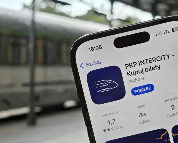 Telefon z aplikacją PKP Intercity na tle pociągu.