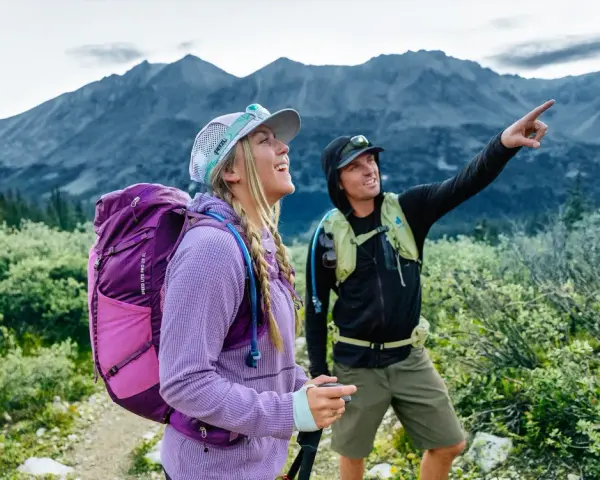 Deux randonneurs s'émerveillent devant un panorama de amm montagne. L'un d'eux pointe du doigt un sommet lointain.