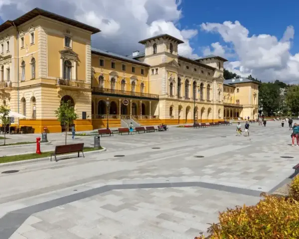 Plac przed sanatorium, gdzie obowiązują nowe zasady wyjazdu do sanatorium na NFZ. Ludzie spacerują po nowoczesnym deptaku.