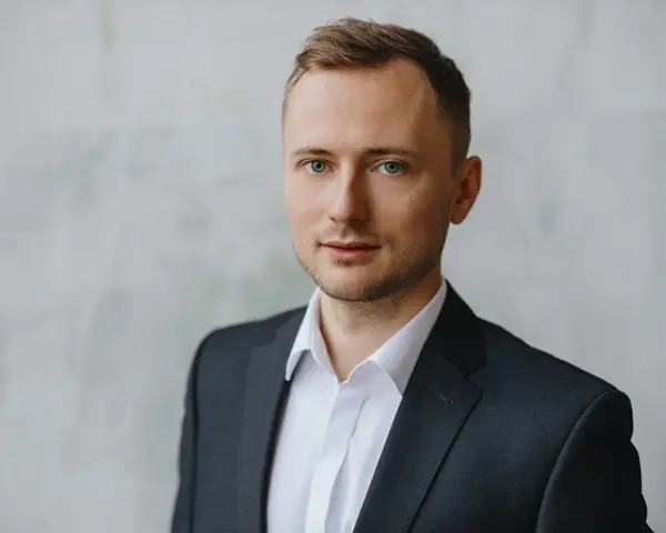 Mężczyzna w garniturze i białej koszuli, idealny przykład, jak zrobić zdjęcie biznesowe w domu.