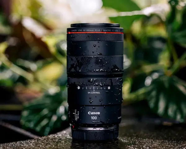 Objectif Canon RF 100mm f/2.8 Macro IS USM, couvert de gouttes d'eau, prêt pour un test en extérieur.