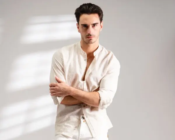 Uomo con outfit bianco e nero, camicia lino con colletto alla coreana e pantaloni chiari.