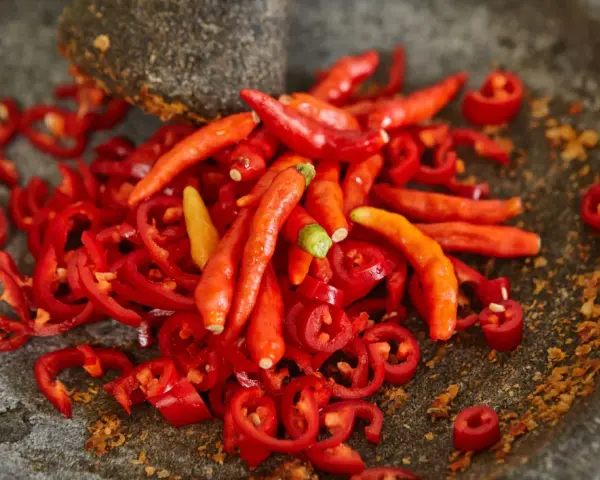 Ostry jak diabli! Całe mnóstwo czerwonych papryczek chili, niektóre pokrojone w plasterki, leżą w kamiennym moździerzu. To zapowiada najostrzejszą paprykę!