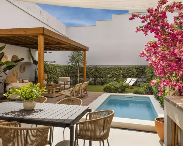 Un patio moderno con piscina, pérgola de madera, zona de estar y comedor exterior. Ideas para decorar un patio con piscina y crear un oasis de relax.