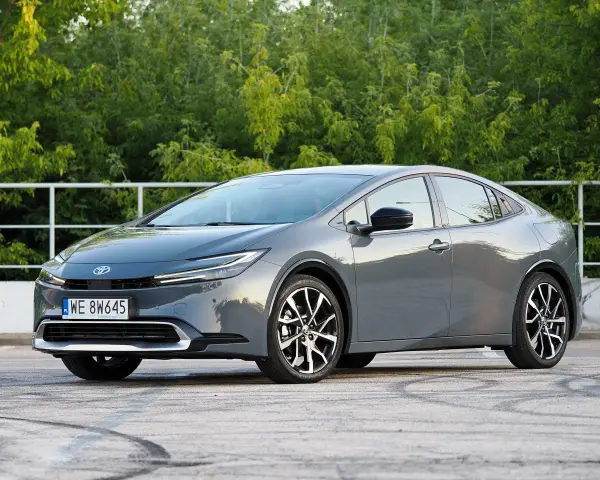 Szary Toyota Prius hybryda na tle zieleni. Zastanawiasz się, ile pali Toyota Prius hybryda? Ten model zachwyca niskim spalaniem.
