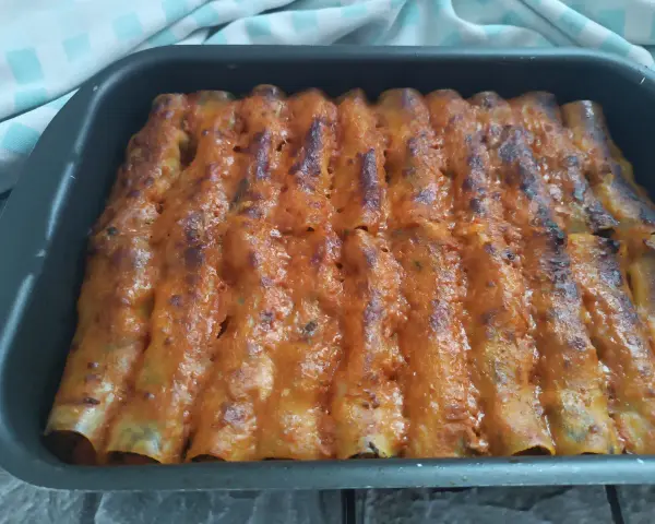 Cannelloni di carne ricetta della nonna, cotti al forno e ricoperti di sugo rosso e formaggio fuso.