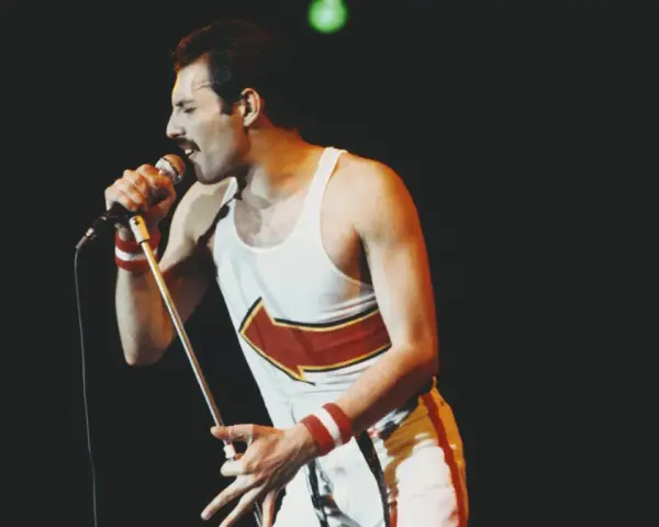 Freddie Mercury, jeden z najlepsi muzycy wszechczasów, śpiewa do mikrofonu na koncercie.