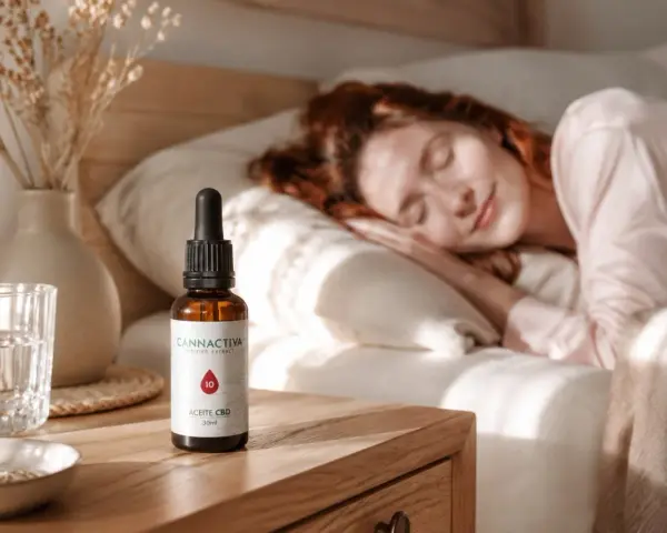 Una mujer duerme plácidamente. A su lado, en la mesita de noche, un frasco de aceite CBD, ideal para saber como tomar aceite de cbd para dormir y disfrutar de un descanso reparador.