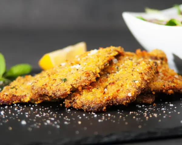 Cotoletta alla palermitana dorata e croccante, guarnita con limone e menta.