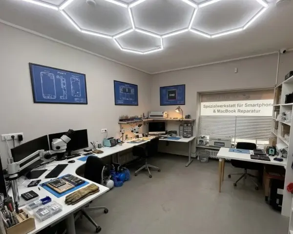 Werkstatt für Smartphone- und MacBook-Reparatur mit Werkzeugen, Mikroskop und technischen Zeichnungen.