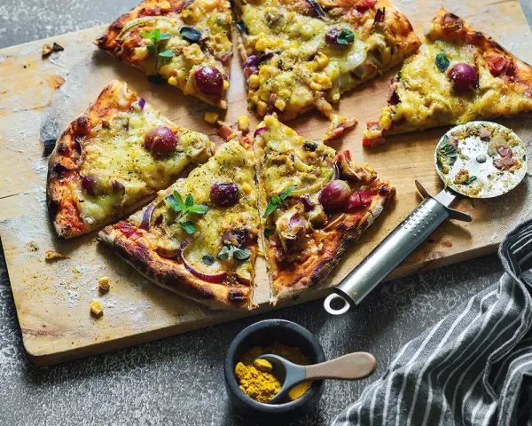 Domowa pizza z kurczakiem, kukurydzą i czerwoną cebulą, pokrojona na kawałki, gotowa do podania.